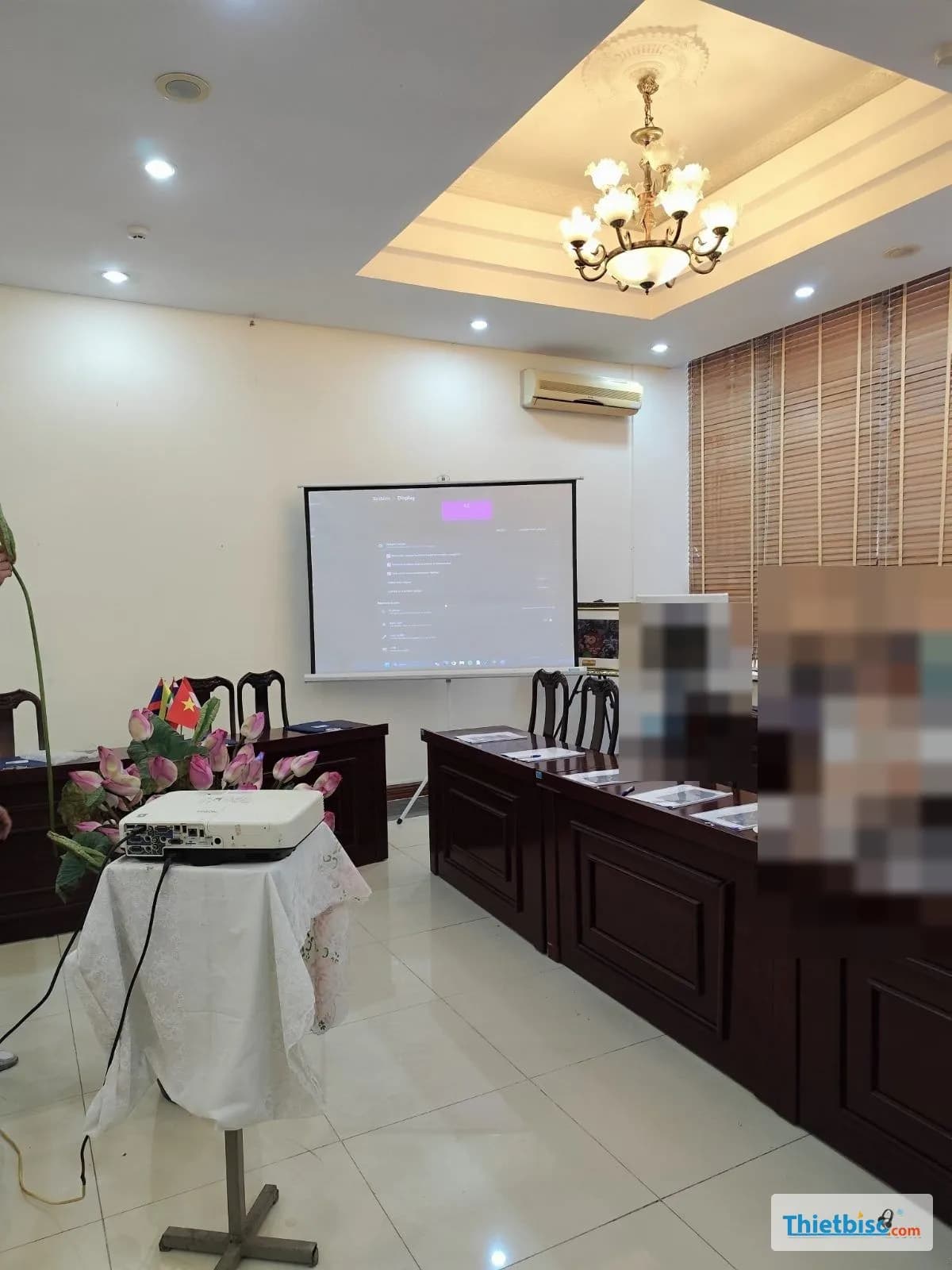 Cho thuê máy chiếu: máy chiếu Epson trên bàn phủ khăn, màn chiếu treo tường trong phòng họp