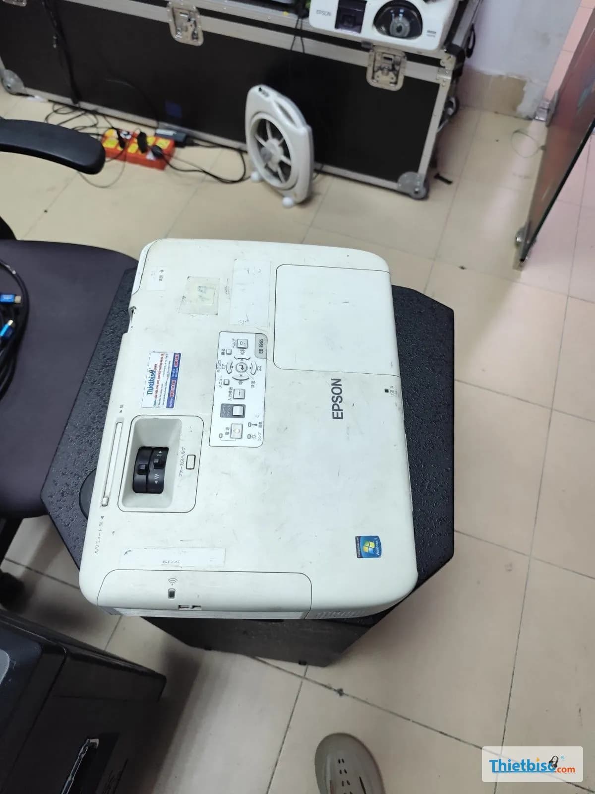 Máy chiếu Epson cho thuê đặt trên loa trong kho, phía sau là thùng kỹ thuật