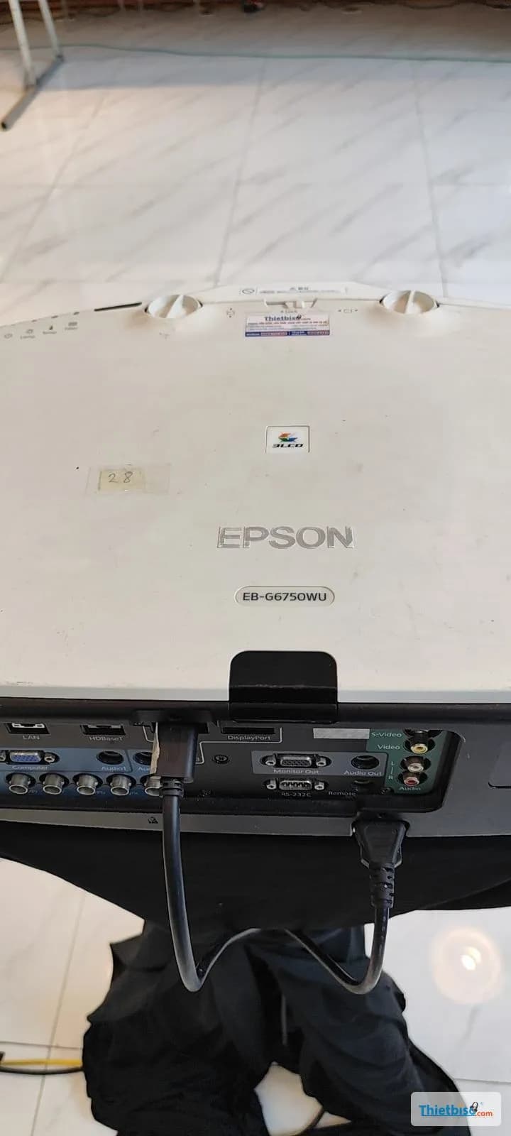 Cận cảnh máy chiếu Epson EB-G6750WU và cụm cổng kết nối phía sau trên bàn phủ vải đen