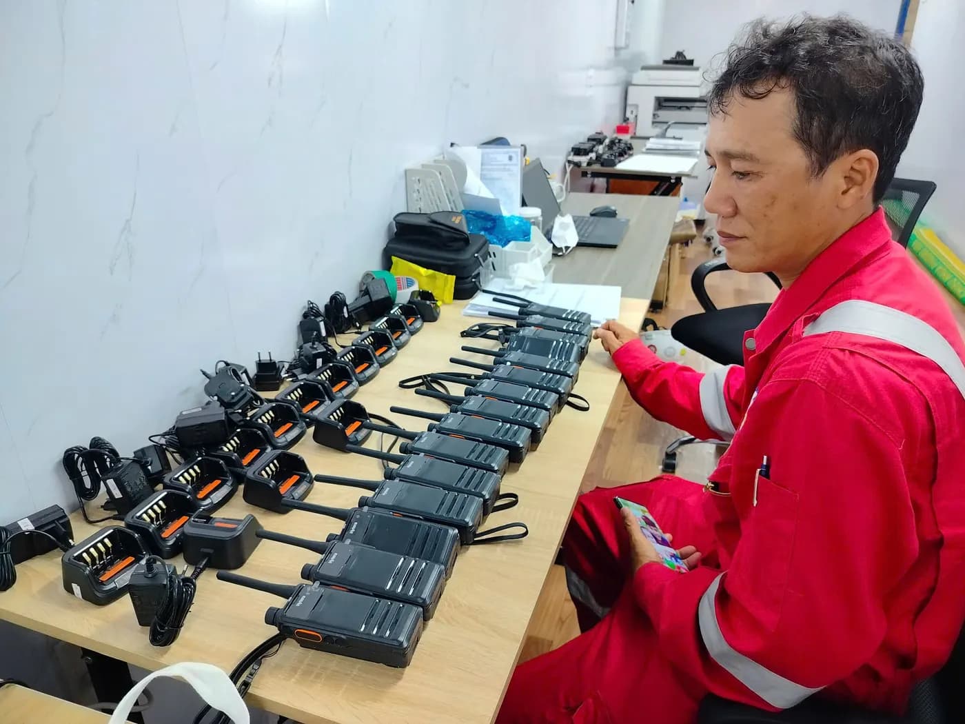 Nhân viên mặc đồ bảo hộ kiểm bộ đàm tại phòng điều hành