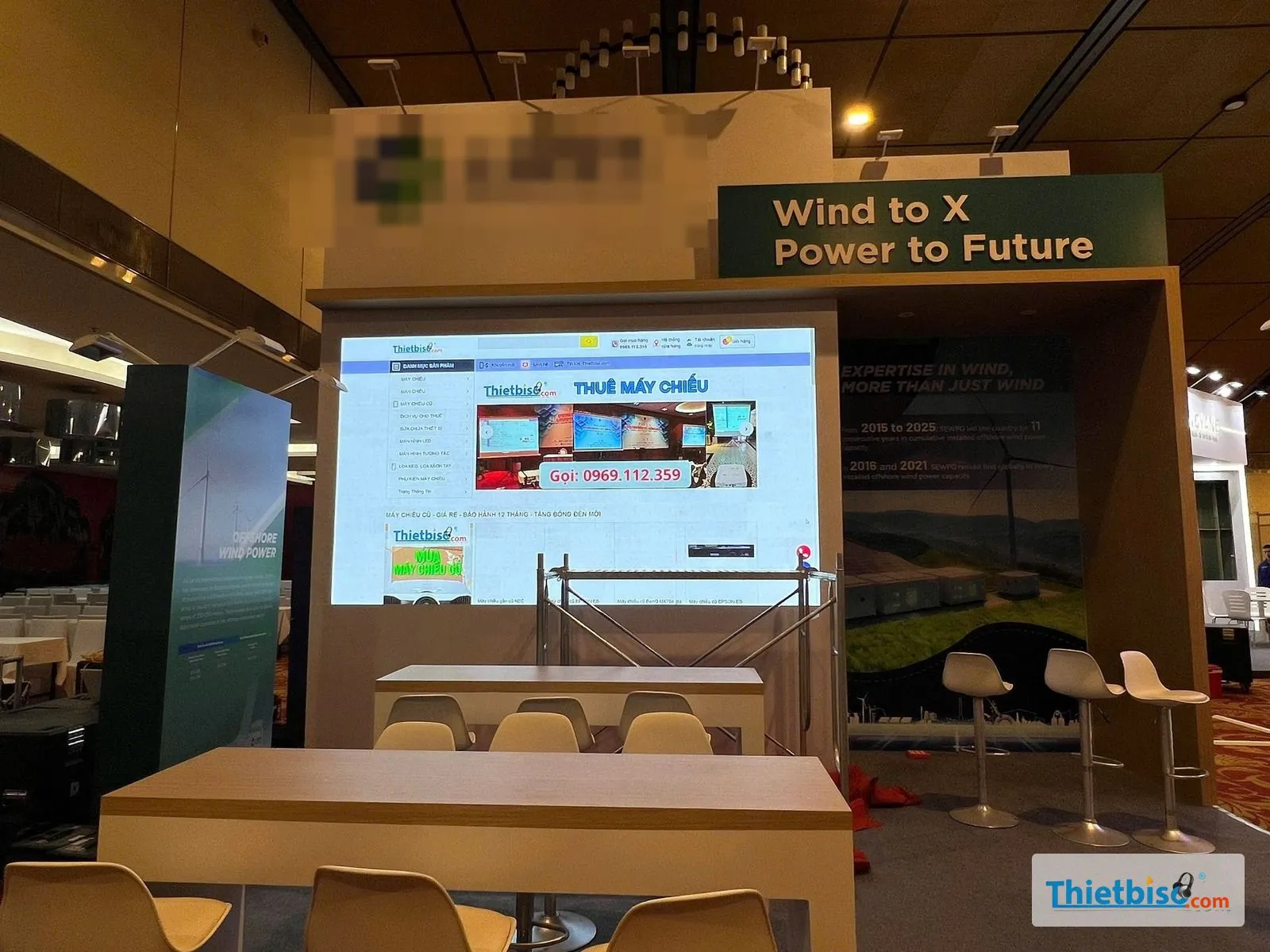 Màn LED lắp trong gian hàng triển lãm hiển thị trang web, trước màn có giàn giáo