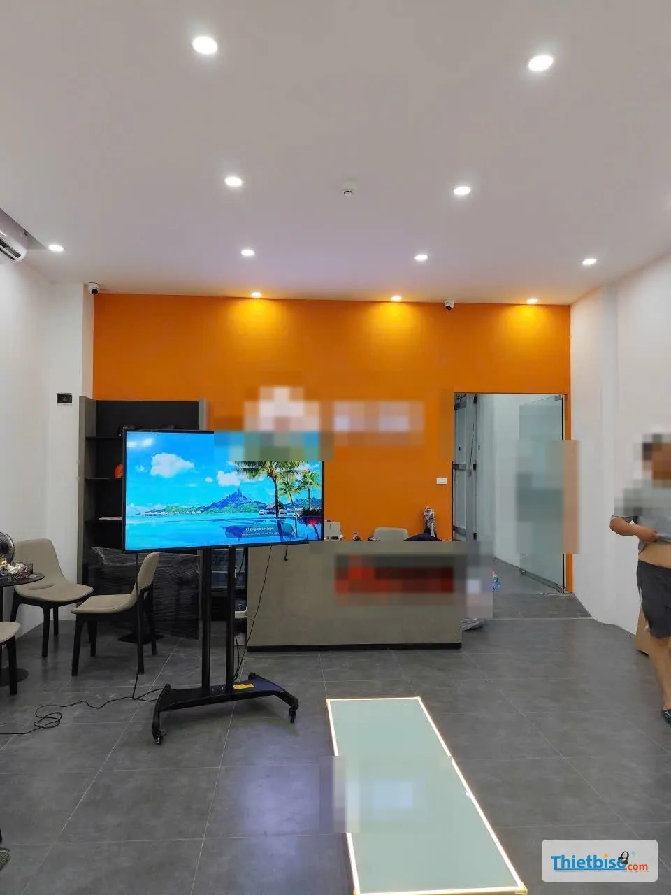 Tivi trên chân đế di động trong sảnh cửa hàng tường cam