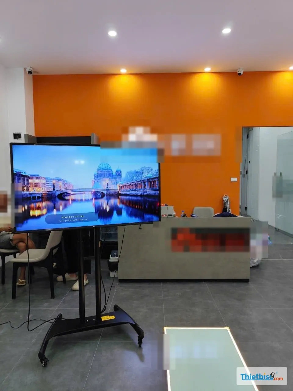 Tivi lớn trên chân đế di động trong cửa hàng tường cam