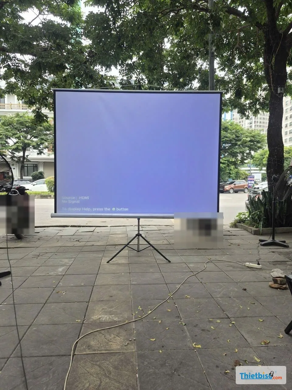 Màn chiếu chân ba càng đặt ngoài trời trên vỉa hè