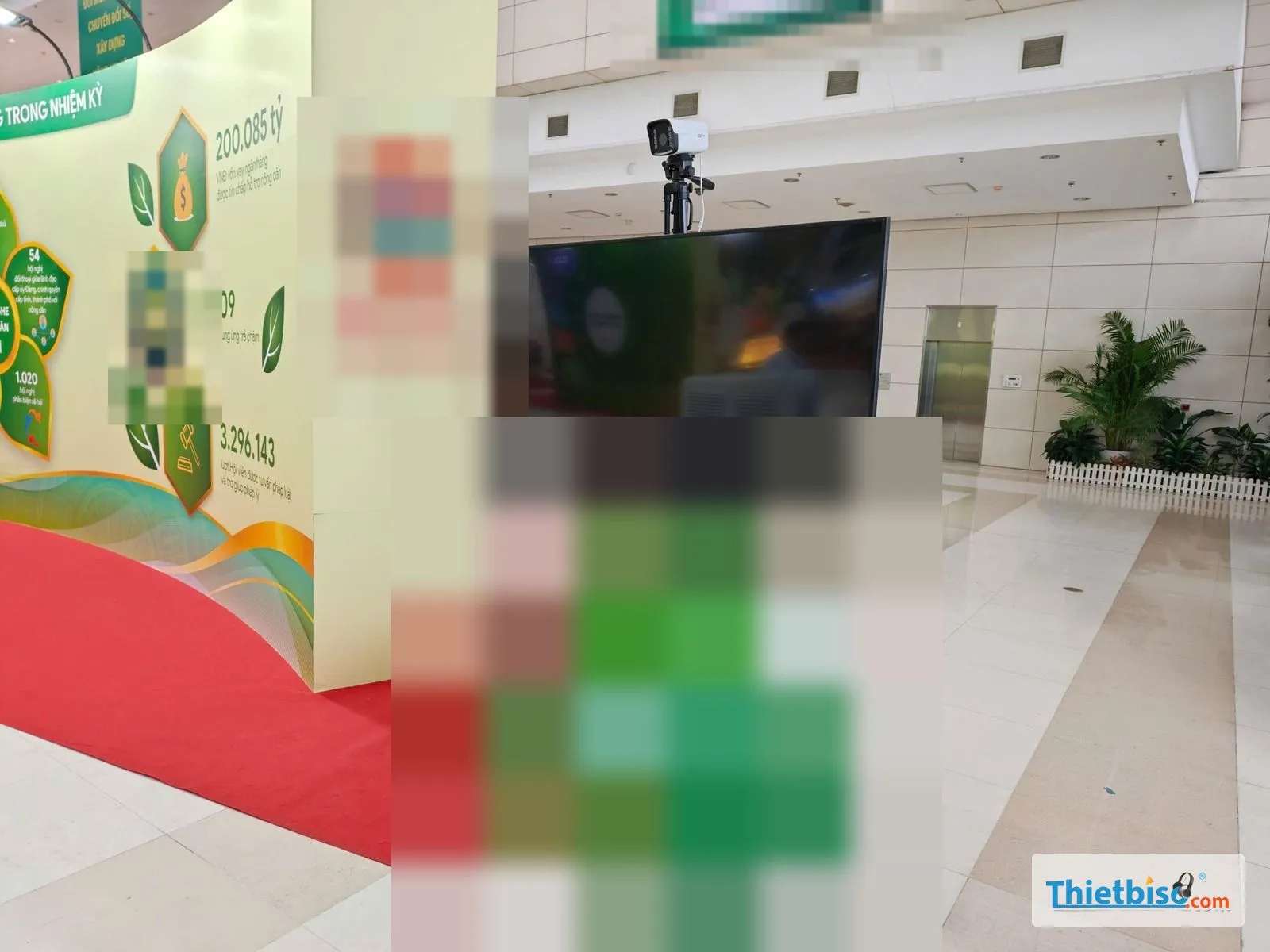 Tivi tắt trên bệ trưng bày xanh cạnh backdrop và thảm đỏ trong sảnh