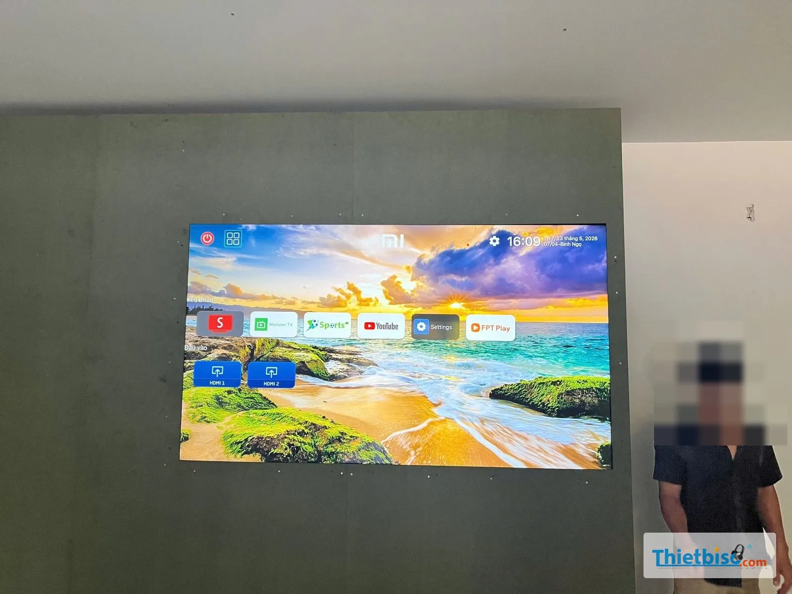 Tivi Xiaomi lắp trên vách tường đang hiển thị màn hình chính