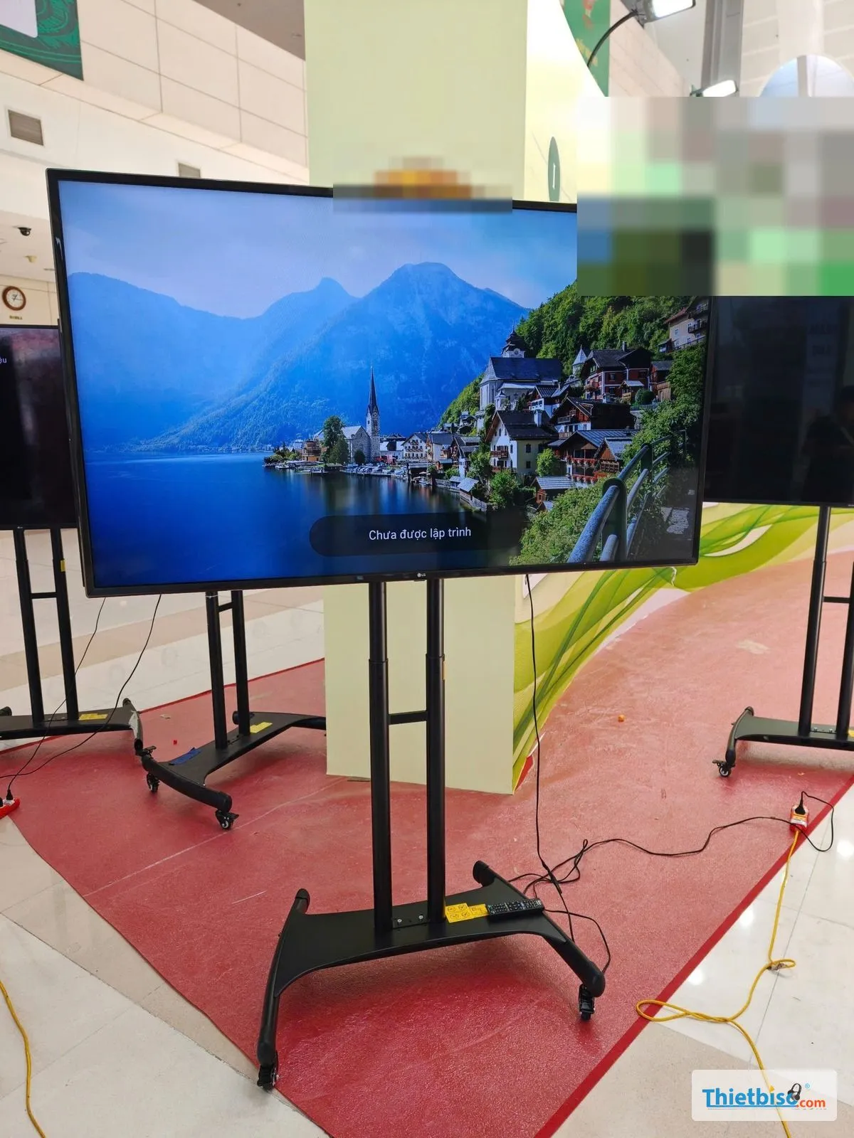 Tivi LG trên chân di động đặt trên thảm đỏ với nhiều tivi phía sau