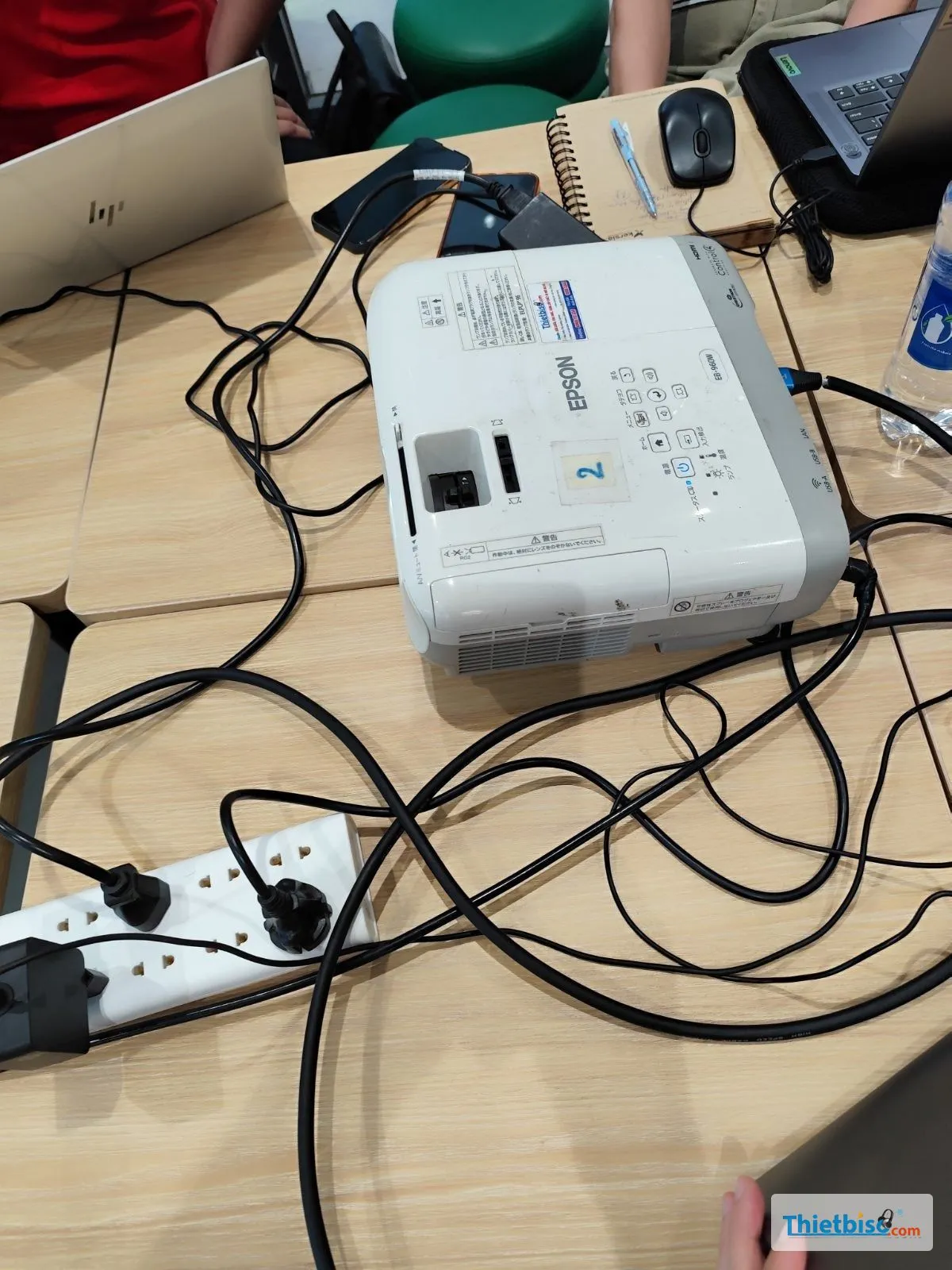 Máy chiếu Epson trên bàn họp cùng laptop, ổ điện và dây cáp