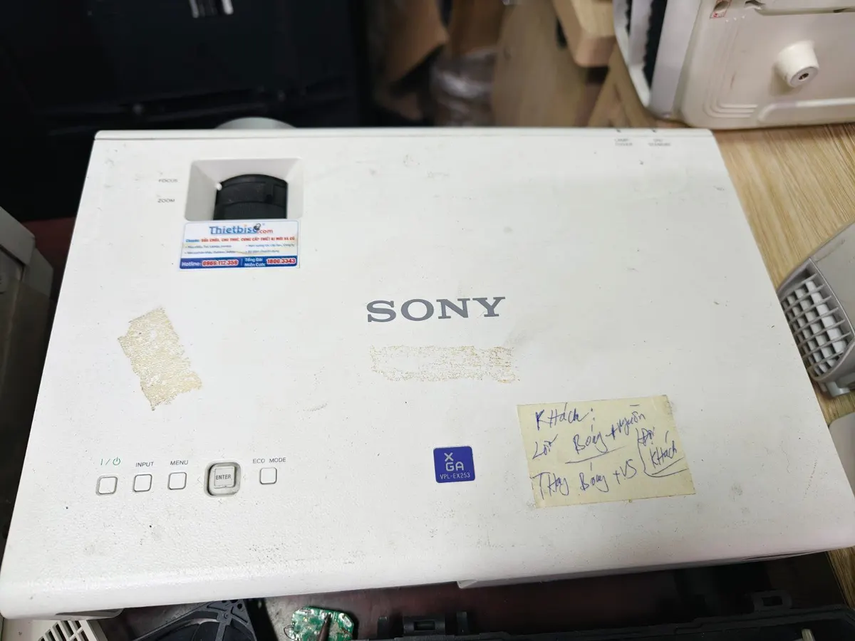 Máy chiếu Sony có tem THIETBISO và giấy ghi chú công việc đặt trên bàn sửa