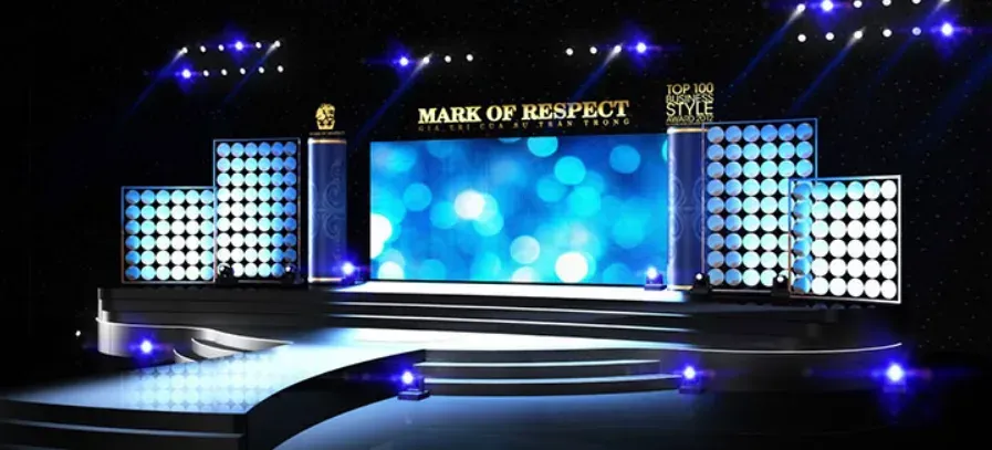 Sân khấu tiệc gala với màn LED trung tâm và hai cụm đèn trang trí hai bên