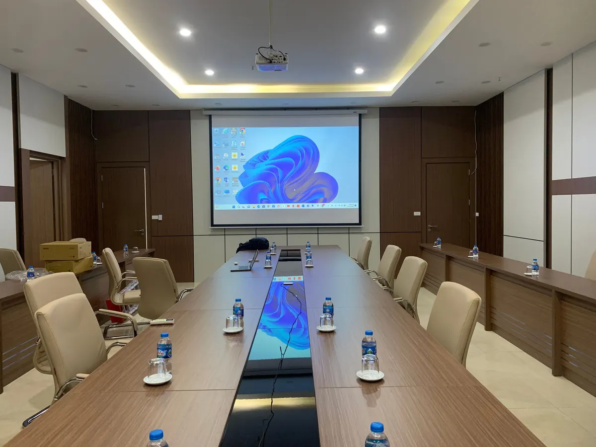Phòng họp dài với màn chiếu treo tường và dãy ghế hai bên bàn