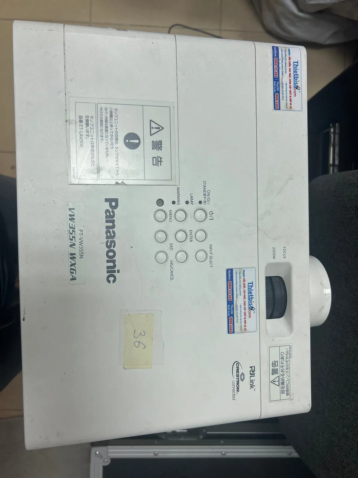 Máy chiếu Panasonic đặt nằm trên sàn, nhìn rõ mặt trên và các nút điều khiển