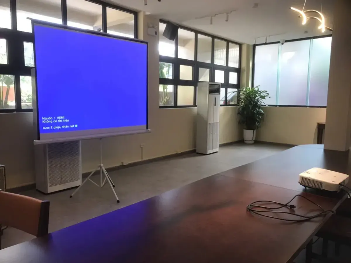Bộ màn chiếu chân cỡ 100 inch trong phòng họp, máy chiếu đặt trên bàn trước màn